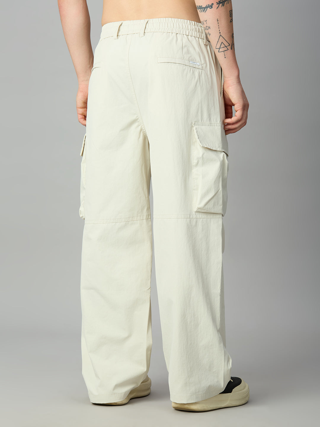 A person shown from the back wearing off-white wide-leg cargo pants with side flap pockets, photographed against a plain light gray studio background.