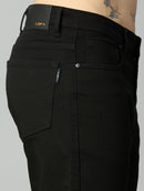 Close-up of waistband, button closure, and premium stitching on men's black stretch denim jeans