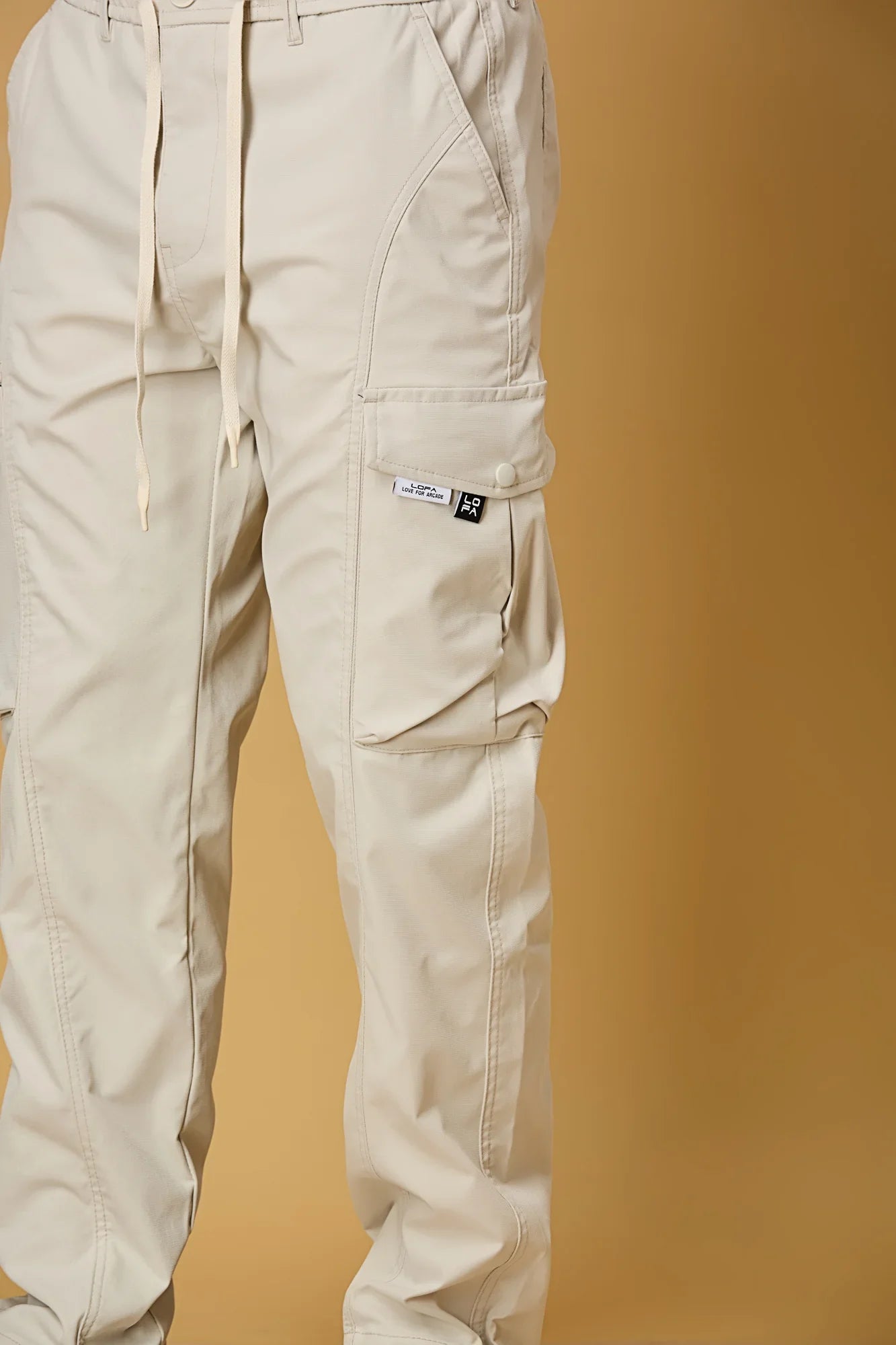 Close-up of beige cargo pants waist string and pocket detailing.