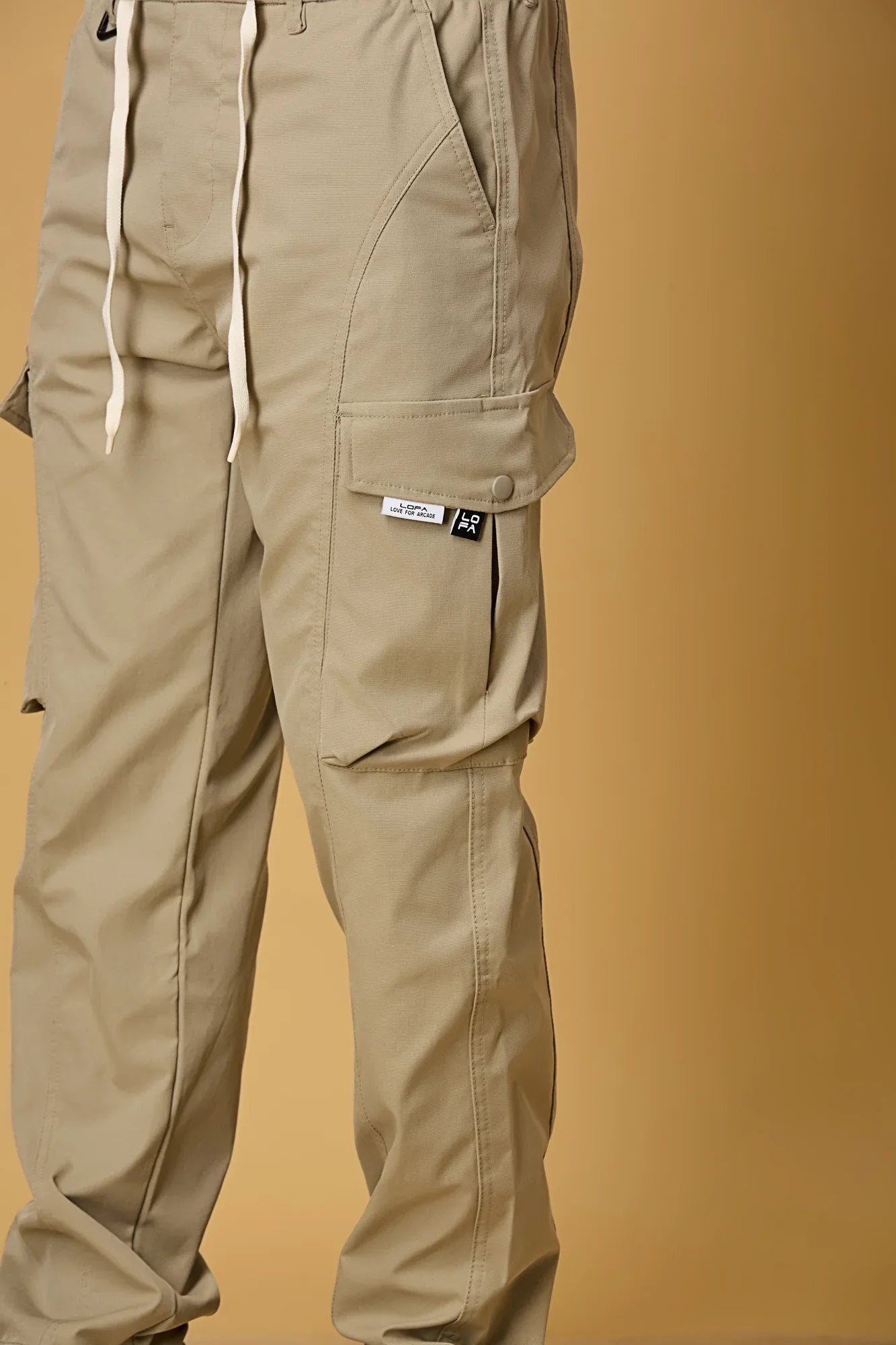 Close-up of Khaki cargo pants, waist string and pocket detailing.