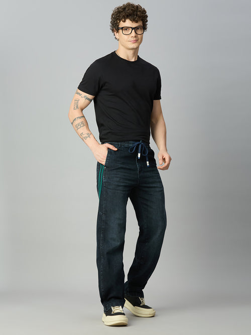 Model wearing The Lofa men's baggy stretch denim jeans with green side stripes and drawstring waistband for a modern streetwear look