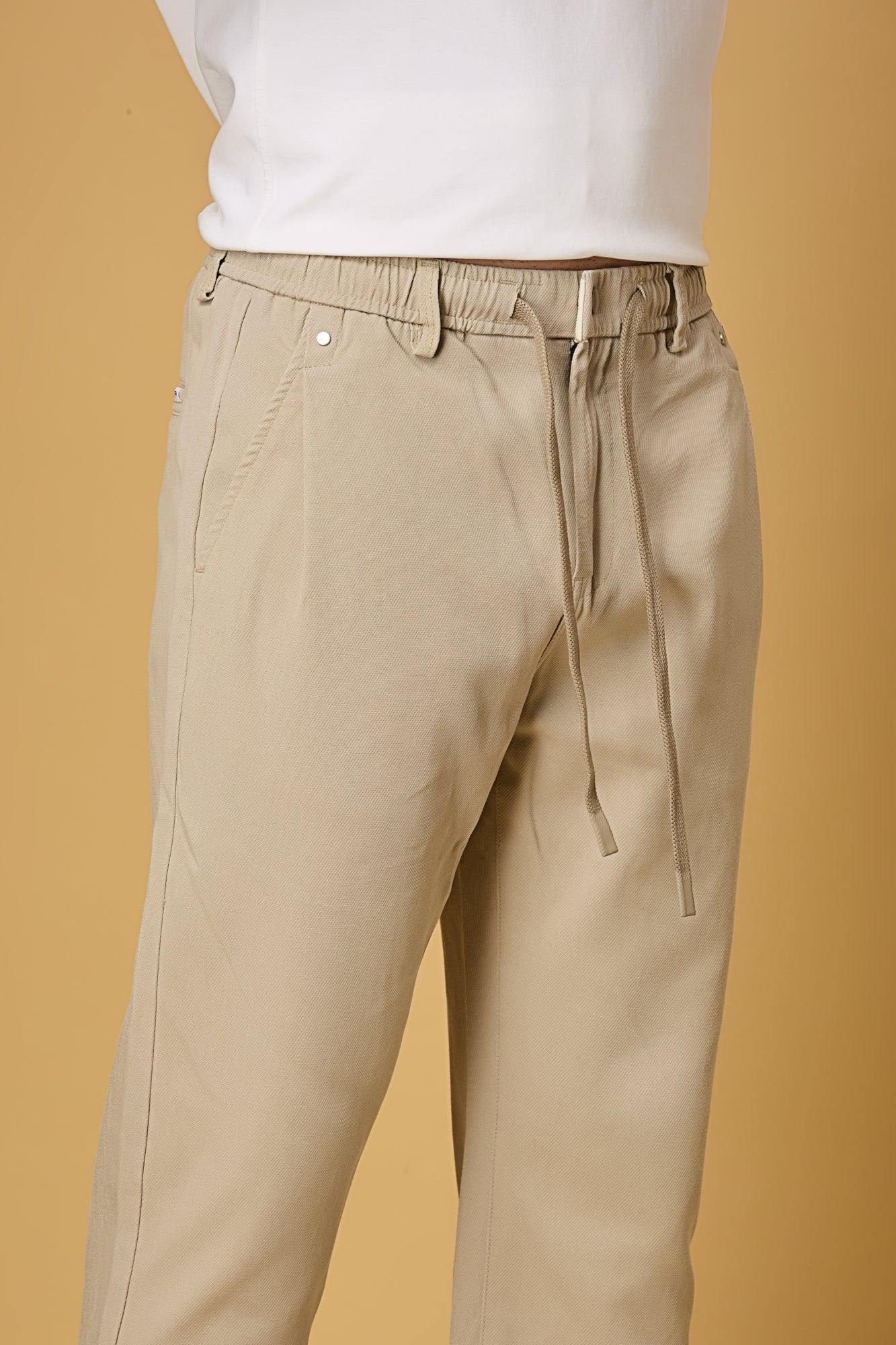 Close-up of waist string, press button, and fabric texture on light khaki trousers.