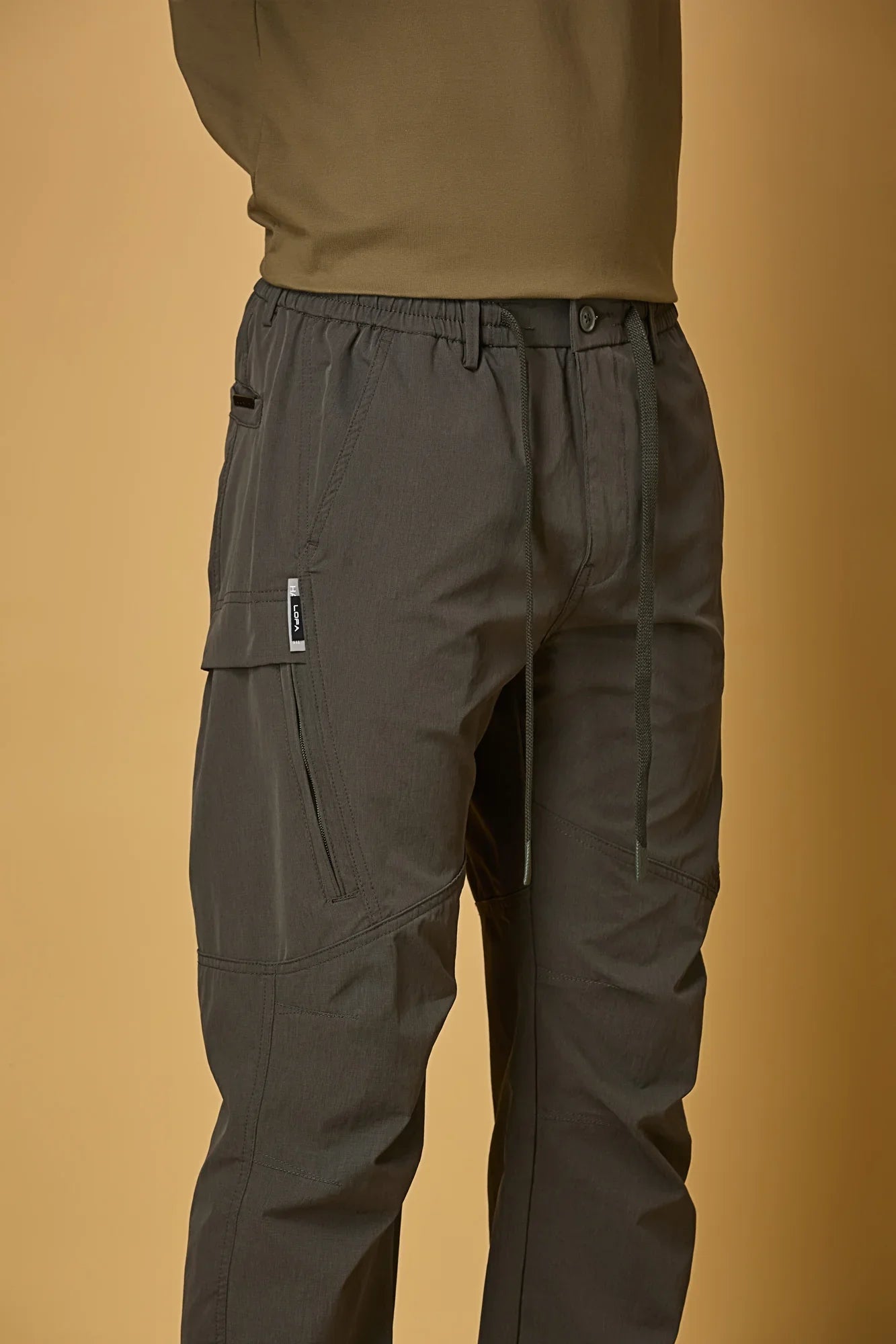 Close-up of grey trousers waist strings, side pockets, and smooth fabric texture.
